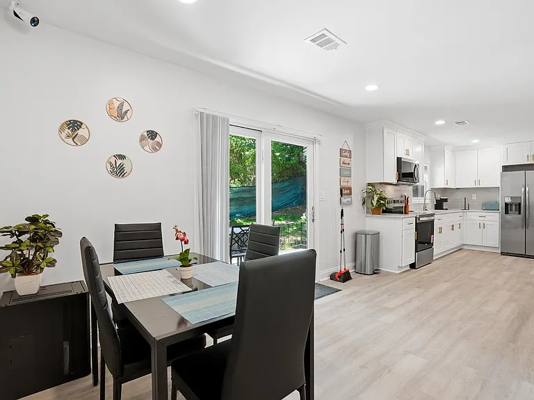 Open kitchen and dining area with stainless appliances, ample cabinetry, and sliding doors leading to an outdoor patio.