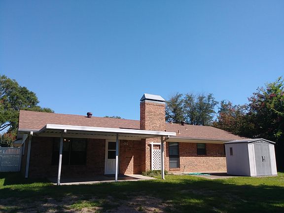 Fenced-in backyard has two concrete patios (one covered) as well as a storage shed.