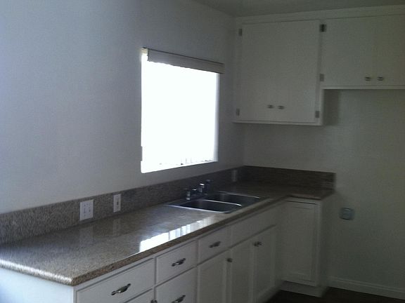 white kitchen cabinets with lots of storage, stainless sink, granite counters and appliances
