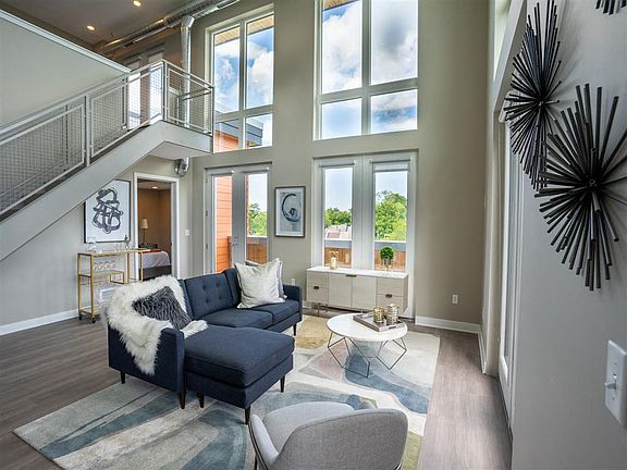 View of great room living area with floor to ceiling windows & stairway to second floor loft in background