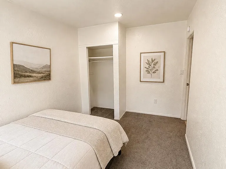Furnished bedroom with plush carpeting and an open closet for convenient storage, plus overhead lighting for easy living.
