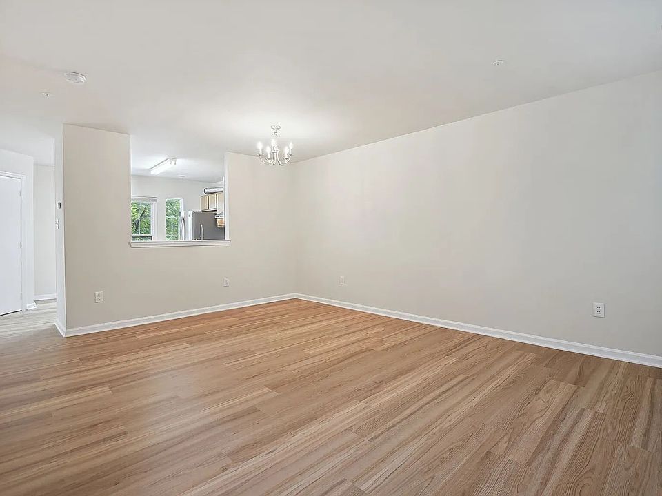 An overview of the living and dining area. The kitchen is visible beyond through the pass-through opening, while the half-bath door is visible on the left.