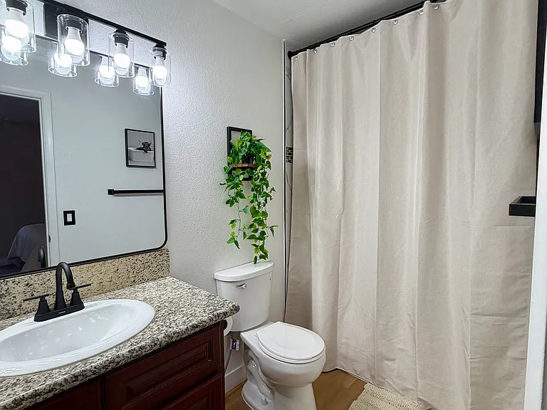 Primary en-suite bathroom with upgraded lighting and fixtures, modern mirror and stylish finishes.