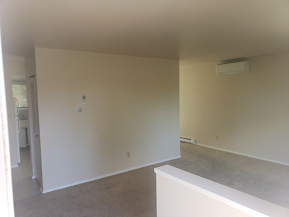 Standing at balcony door looking into living room. Air conditioner head on wall in background