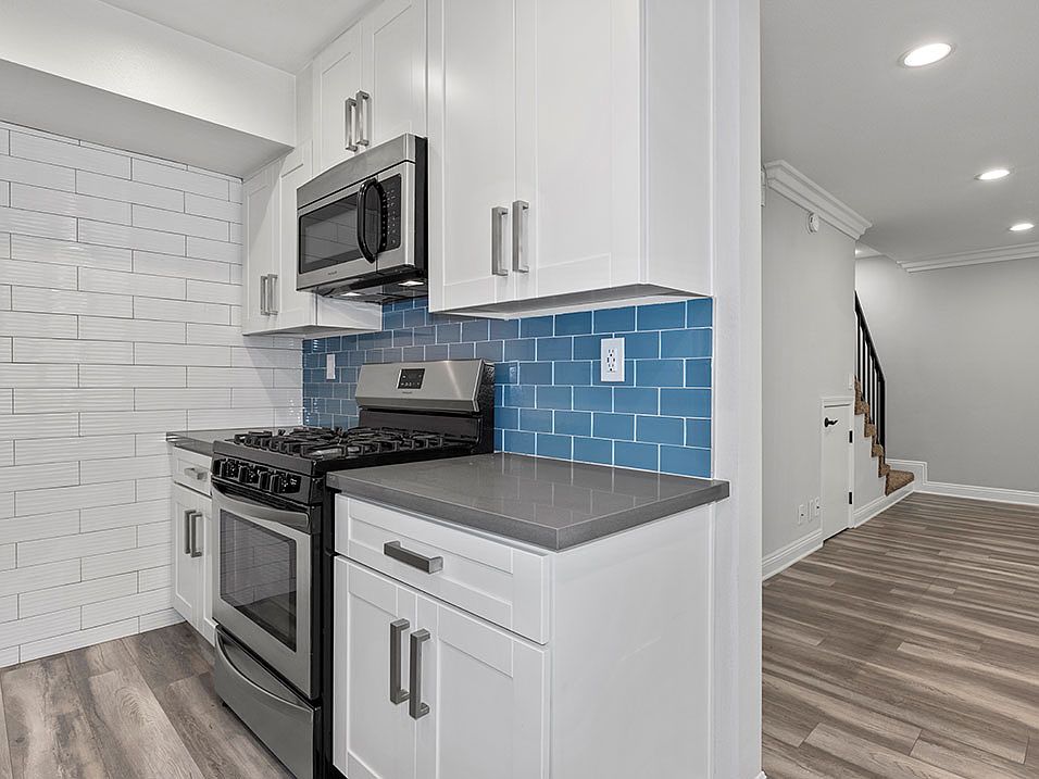 Blue tiled kitchen with stainless steel oven and fixtures.