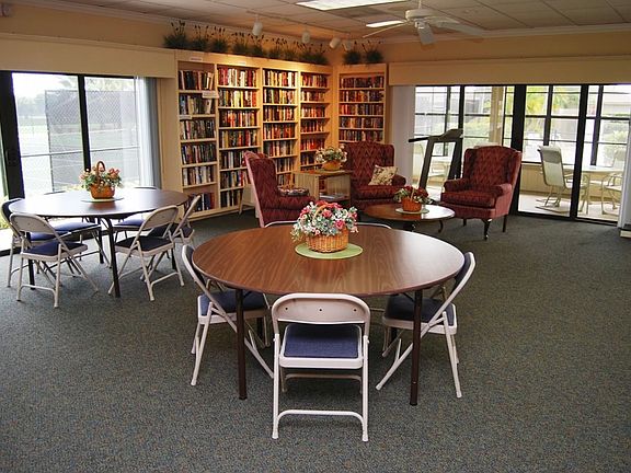 The clubhouse's free library and screened in porch containing tables, chairs, and a large sectional couch.