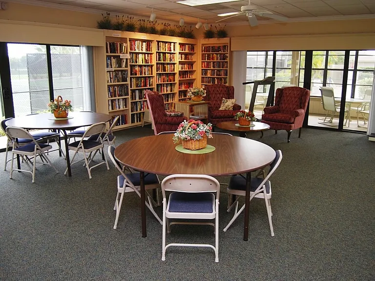 The clubhouse's free library and screened in porch containing tables, chairs, and a large sectional couch.