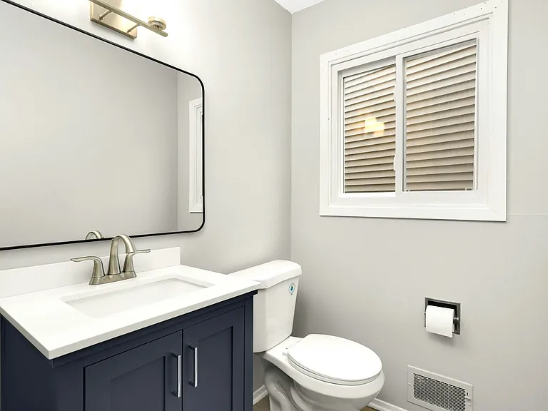 Updated main-level half bath with modern vanity, lighting, and fixtures