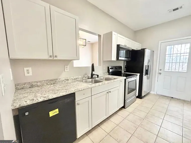 Updated kitchen with ample cabinetry, granite-look counters, double sink, and a full appliance suite with exterior door acces