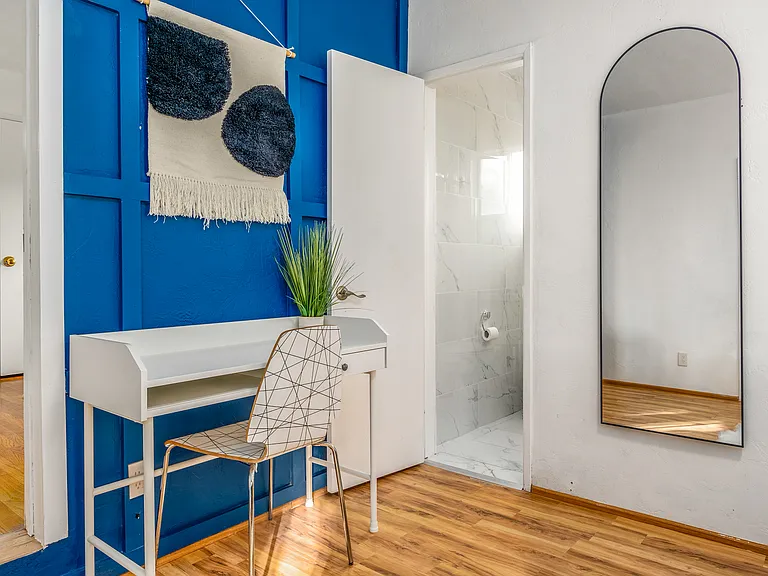 Polished hardwood floors radiate warmth and timeless sophistication.
Thoughtfully arranged decor and airy design lead seamlessly to a private ensuite bathroom.