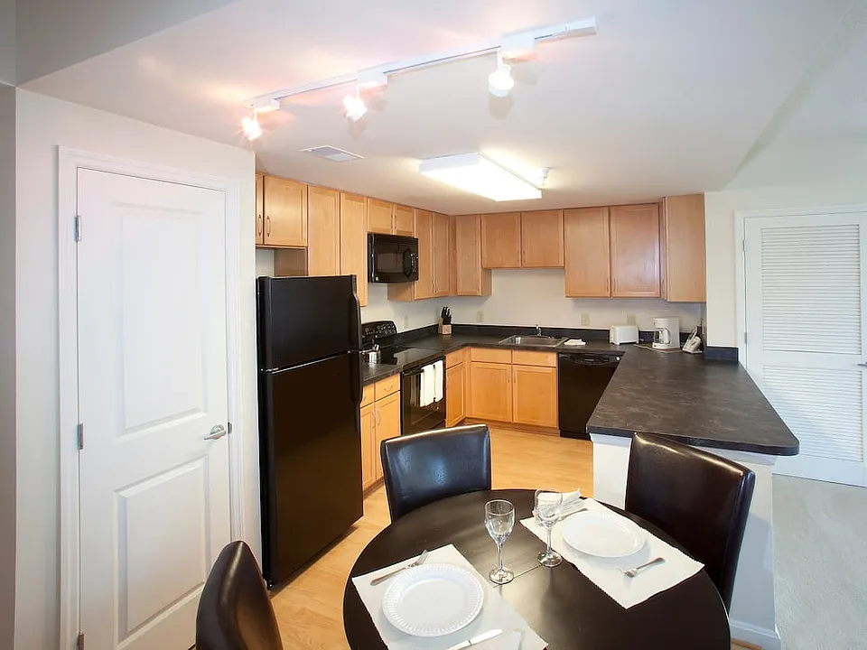 Dining area and kitchen with black appliances, black countertops and hard surface flooring