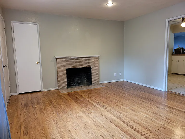 the entry of the house is the front living room space with a wood burning fireplace, entry closet, real hardwood floors,