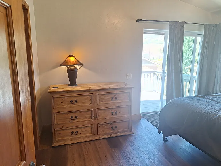 Rear master bedroom dresser, queen size bed and sliding glass patio door to deck.