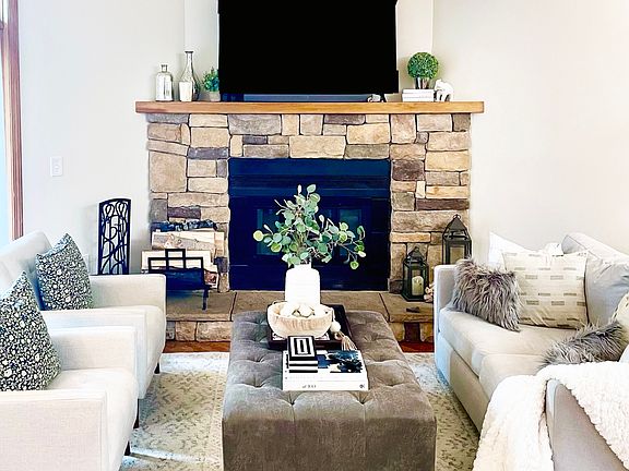 Great room with wood-burning fireplace, dining banquette and wall of windows opening to a private deck
