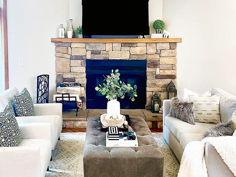 Great room with wood-burning fireplace, dining banquette and wall of windows opening to a private deck
