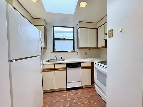 Galley kitchen with skylight and window over the sink.