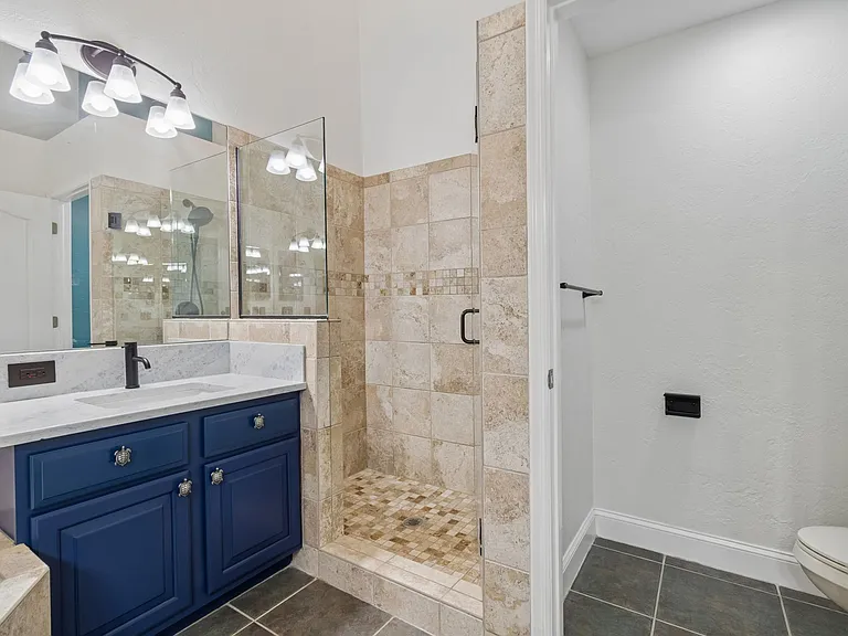 This sanctuary features a sprawling primary suite complete with dual luxury vanities, a deep soaking tub, a custom walk-in shower, a private toilet room, and a large walk-in closet.