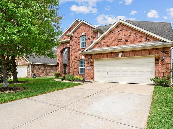 Side view of 13906 Pawnee Trails Dr. illustrating ample sized 2-car garage and driveway pad.