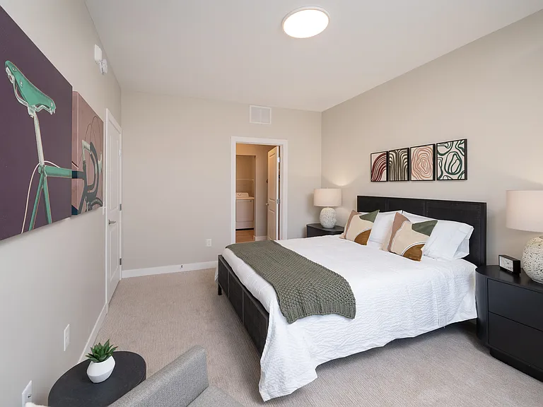 A large, open bedroom with plush carpet and an oversized window for natural light.