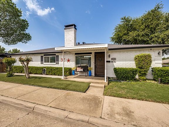 White brick exterior with a dark shingled roof and a covered entryway