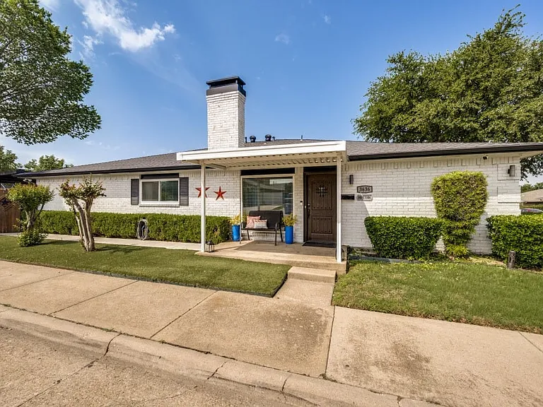 White brick exterior with a dark shingled roof and a covered entryway
