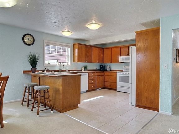 Large kitchen area with tile floor and solid wood cabinets with plenty of storage.