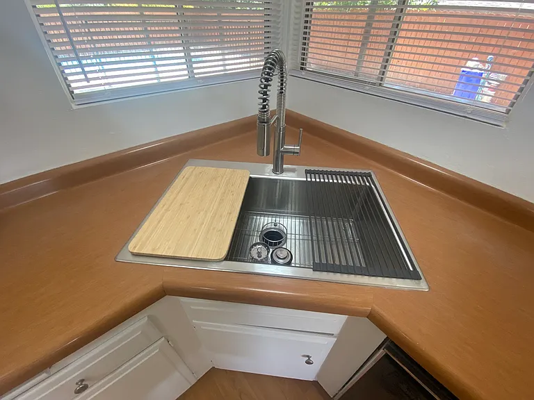 New stainless-steel farmhouse sink with cutting board, drying rack, and new disposal.