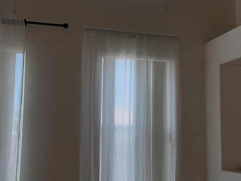 Living room windows with blinds and white curtains