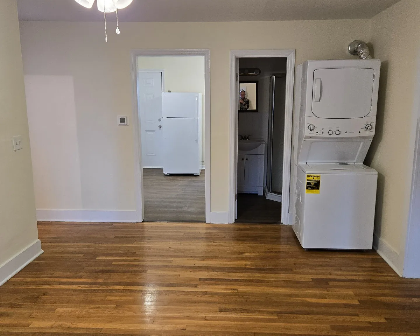 Livingroom w/ washer-dryer, view into kitchen and bathroom. Front entrance stairs out of view to the far left