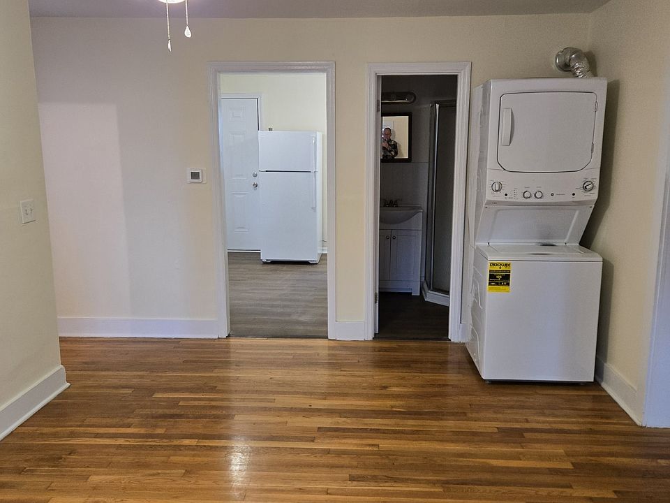 Livingroom w/ washer-dryer, view into kitchen and bathroom. Front entrance stairs out of view to the far left