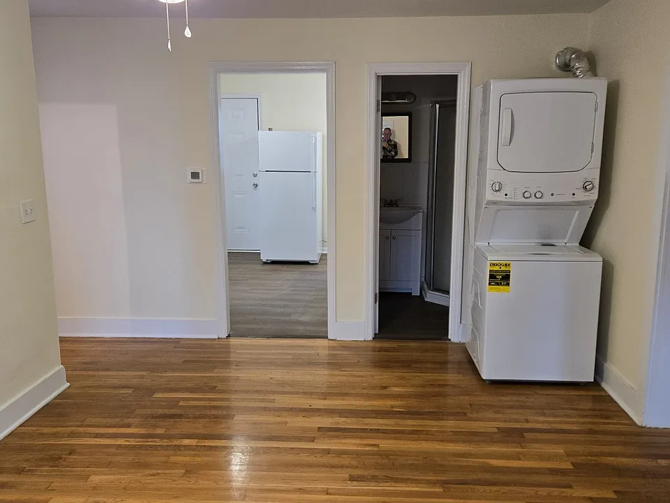 Livingroom w/ washer-dryer, view into kitchen and bathroom. Front entrance stairs out of view to the far left