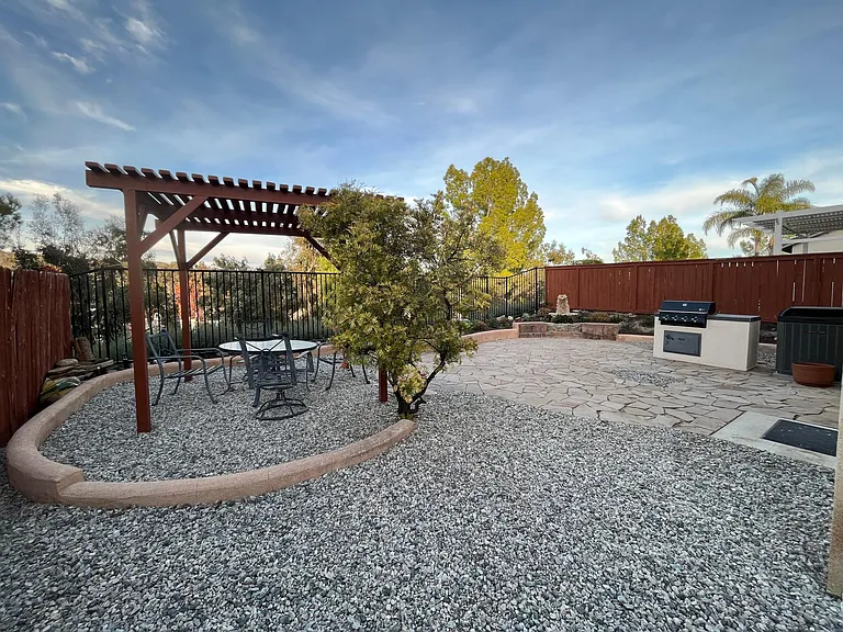 Large, fully landscaped rear yard with pergola, gas BBQ, and stunning views.