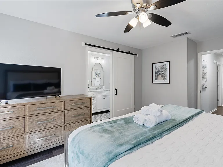 Primary Bedroom with King Sized Plush Bed, Bedside Chests with 3 Drawers with Lamps, Full Sized Dresser with Large Flat Screen Smart TV