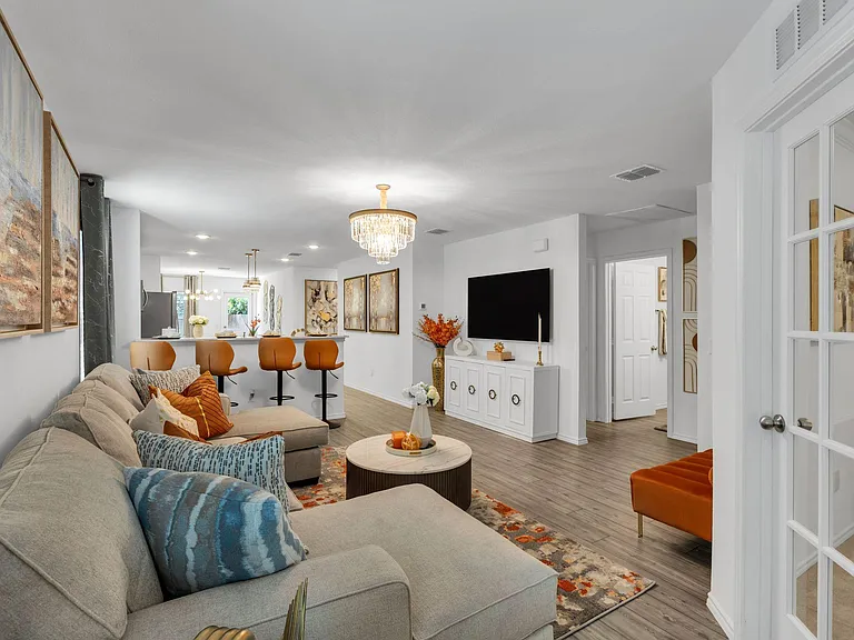 Open-concept living area with a sectional, media wall, and bar seating that flows into the kitchen for easy entertaining.