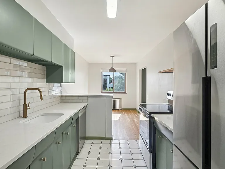 Bright and modern kitchen with sleek stainless steel appliances, mint green cabinetry, and elegant white countertops.