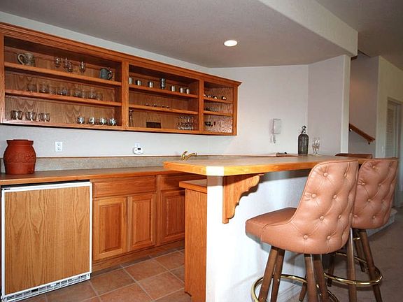"Custom wet bar with fridge, sink and tile flooring."