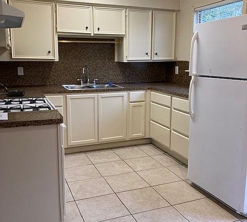 Updated kitchen includes fridge and gas stove.
