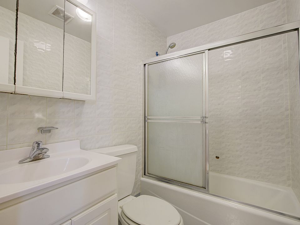 Full bath featuring tile walls, vanity, and bath / shower combo with glass door