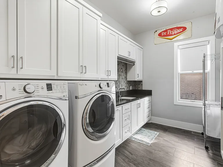 Laundry room with washer + dryer, plus a sink and plenty of storage.