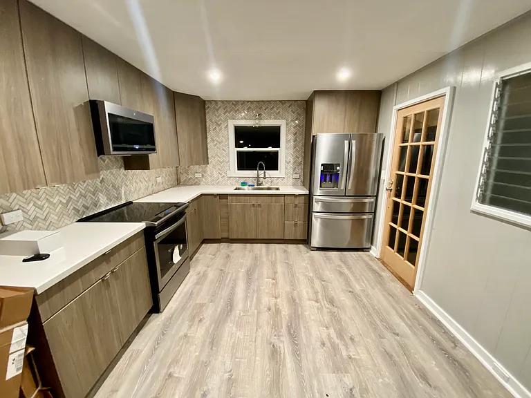 Beautifully renovated kitchen featuring modern cabinetry, quartz countertops, designer tile backsplash, stainless steel appliances, and abundant natural light_blending contemporary comfort with classic beach house charm. ___