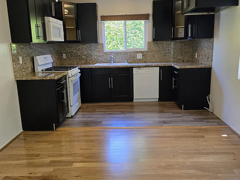 This view is from the dining room looking into the kitchen with wood glass cabinets, granite counters, dishwasher, self cleaning stream oven, disposal, microwave and automatic light of kitchen