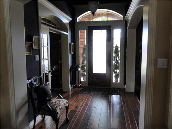 Extra wide entry hall shows wood  faced openings and high ceiling.  Ceiling is faux painted