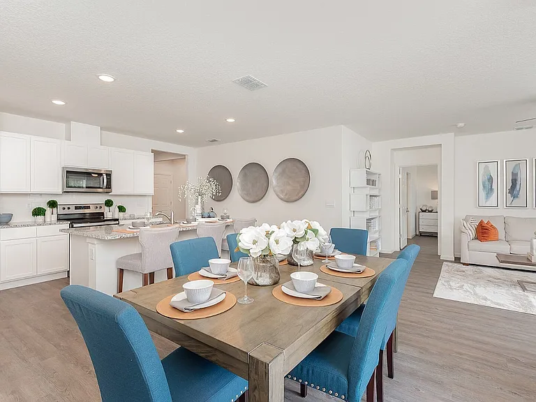 Chic open-plan living area with a modern kitchen, elegant dining setup, and inviting living room. Features vibrant blue chairs and tasteful decor.