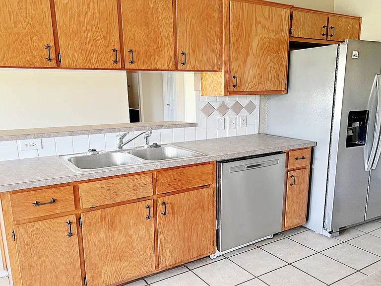 Kitchen sink, dishwasher, refrigerator & bar toward living area