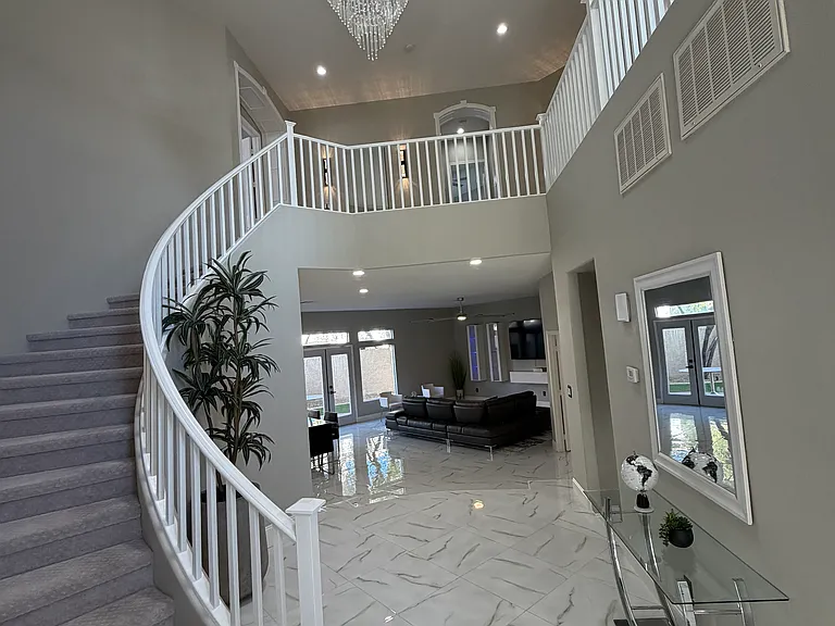 Elegant foyer view connecting the curved staircase, upper-level loft, and main living area.