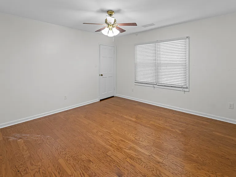 Warm and welcoming bedroom featuring rich hardwood floors, ceiling fan, and natural light _ ready for you to call home.