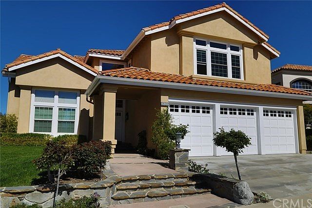 The front of the home showing 3 car garage, custom hard scope and land scape as well as a large driv