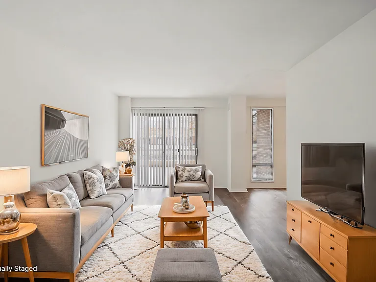 A living room with a grey couch, a wooden coffee table, and a television.