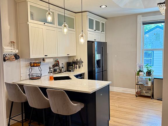 An open kitchen with higher ceilings and a chandelier with bar seating.