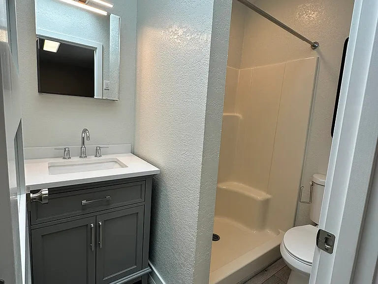 Large shower, with new medicine cabinet, vanity unit, and flooring.